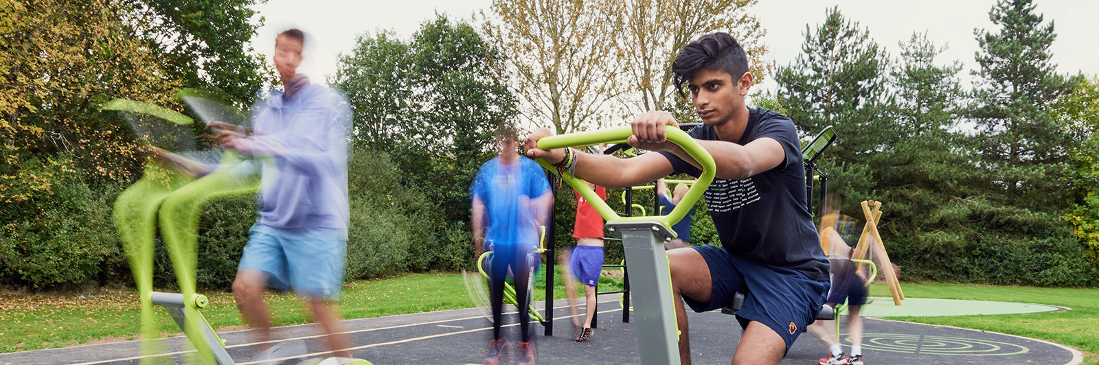 Group of adults are exercising on outdoor fitness equipment for recreational areas.